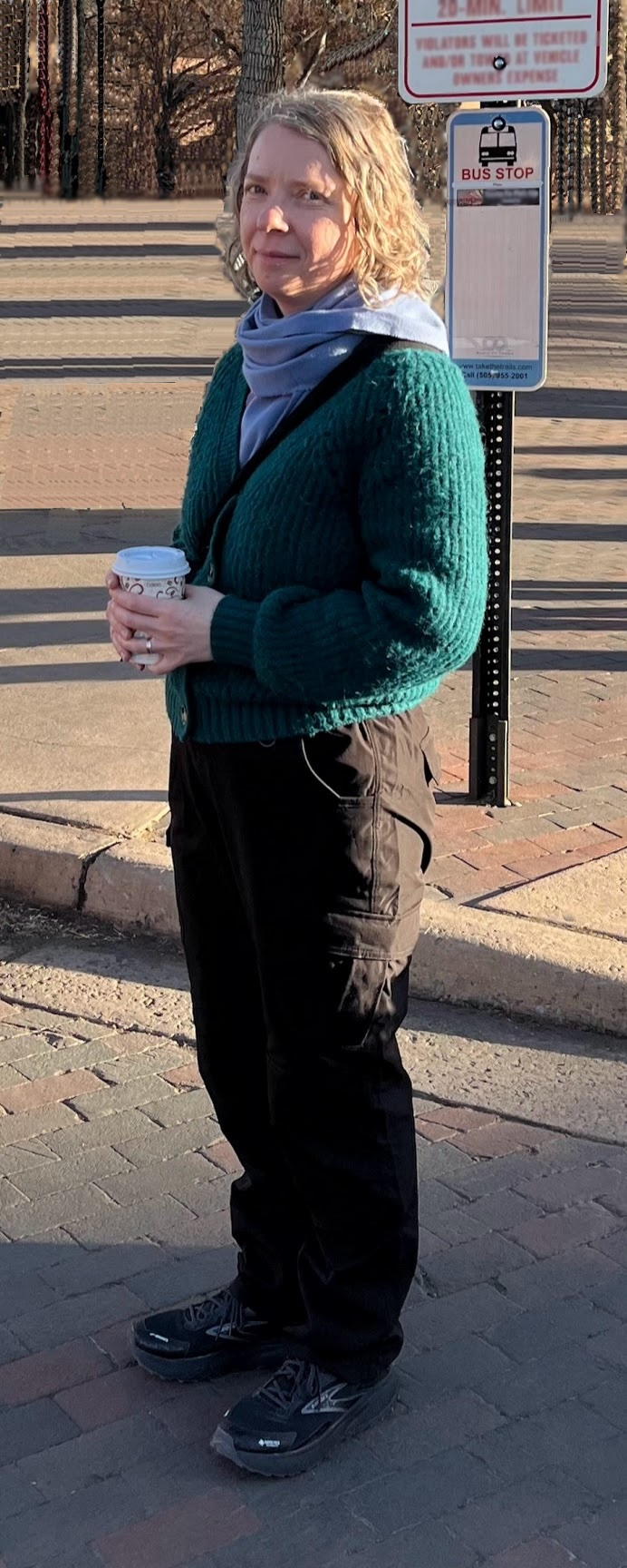 Dr. Oksana Bihun at a bus stop holding a coffee cup